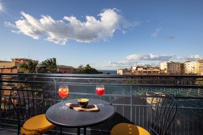 A balcony with a table, two chairs, and two drinks.