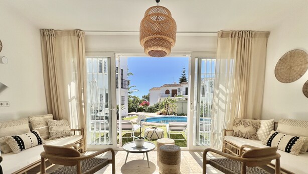 Amplia sala de estar con vista a una piscina y mobiliario exterior.