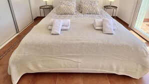 Un dormitorio amplio con una cama grande, dos lámparas de noche y tres adornos de pared tejidos.