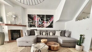 Una sala de estar moderna con un sofá seccional gris, una chimenea y un cuadro abstracto grande.