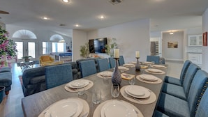 Un comedor moderno con una mesa larga dispuesta para seis personas, rodeada de sillas tapizadas en azul.