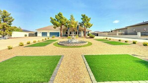 Una propiedad residencial con un camino de acceso circular central, una fuente y un diseño de jardín simétrico.