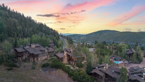 Un chalet de montagne doté de plusieurs cabanes, d’une piscine et offrant une vue panoramique sur la forêt et les montagnes environnantes.