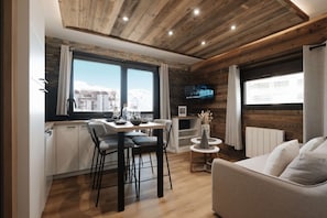 Ein modernes Interieur mit Essbereich, einer Couch und einem an der Wand befestigten Fernseher.