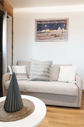 Una sala de estar con un sofá, almohadas y un cuadro en la pared.