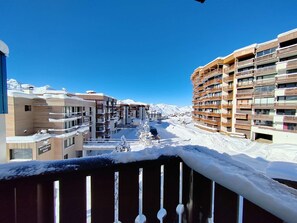 Ein Hotel mit mehreren Etagen, Balkonen und Blick auf schneebedeckte Berge.
