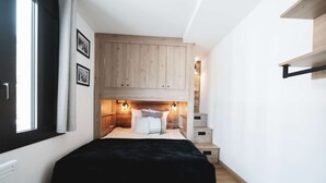 Un dormitorio con cama, armario de madera y estanterías empotradas.