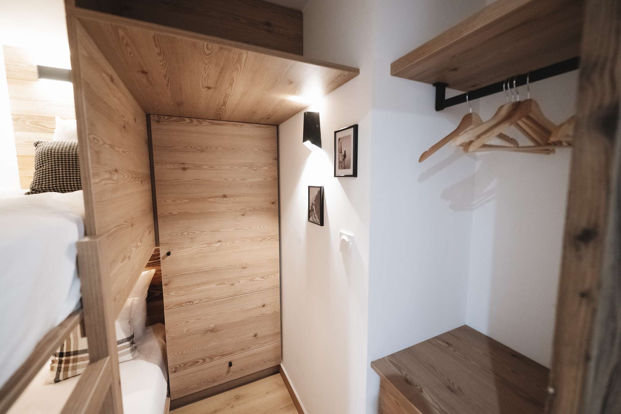 A compact room with a wooden wardrobe, a bed, and a small table.