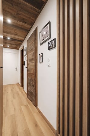 Ein Korridor mit Holzwandverkleidung, einer Holztür und gerahmten Bildern an der Wand.