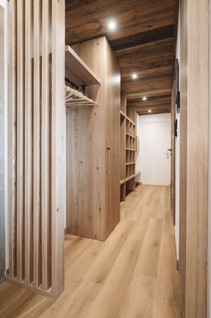A wooden interior with a closet, shelves, and a door.