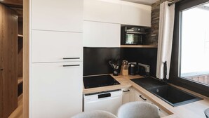 Una cocina compacta con armarios blancos, encimera negra y horno empotrado.