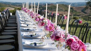 A long dining table set for a meal with white plates, silverware, and pink flowers. - Exclusive, luxurious Villa. Unique location near Certaldo (Certaldo)