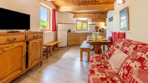 A cozy living room with a wooden ceiling, a television, a sofa, and a dining area. - Appartement Grand Roc 2, Argentière (Chamonix), France (Argentière (Chamonix))