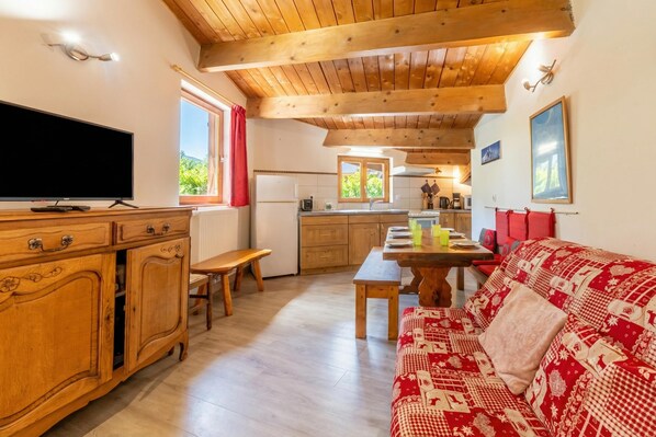 Uma sala de estar aconchegante com teto de madeira, televisão, sofá e um espaço para refeições.