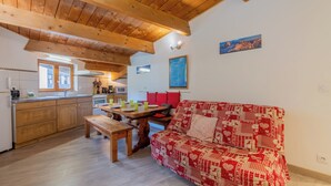 A cozy kitchen with wooden cabinets, a dining table, and a red patterned sofa. - Appartement Grand Roc 2, Argentière (Chamonix), France (Argentière (Chamonix))