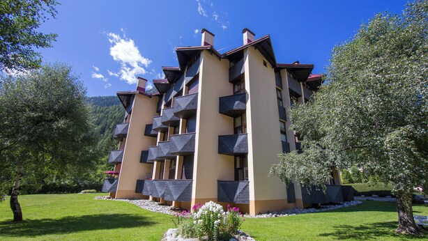 A multi-story hotel with balconies, surrounded by greenery and trees. - Appartement Grand Roc 2, Argentière (Chamonix), France (Argentière (Chamonix))