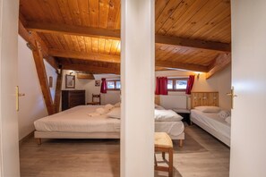 Cozy attic bedroom with two single beds, wooden bench, and small table.
