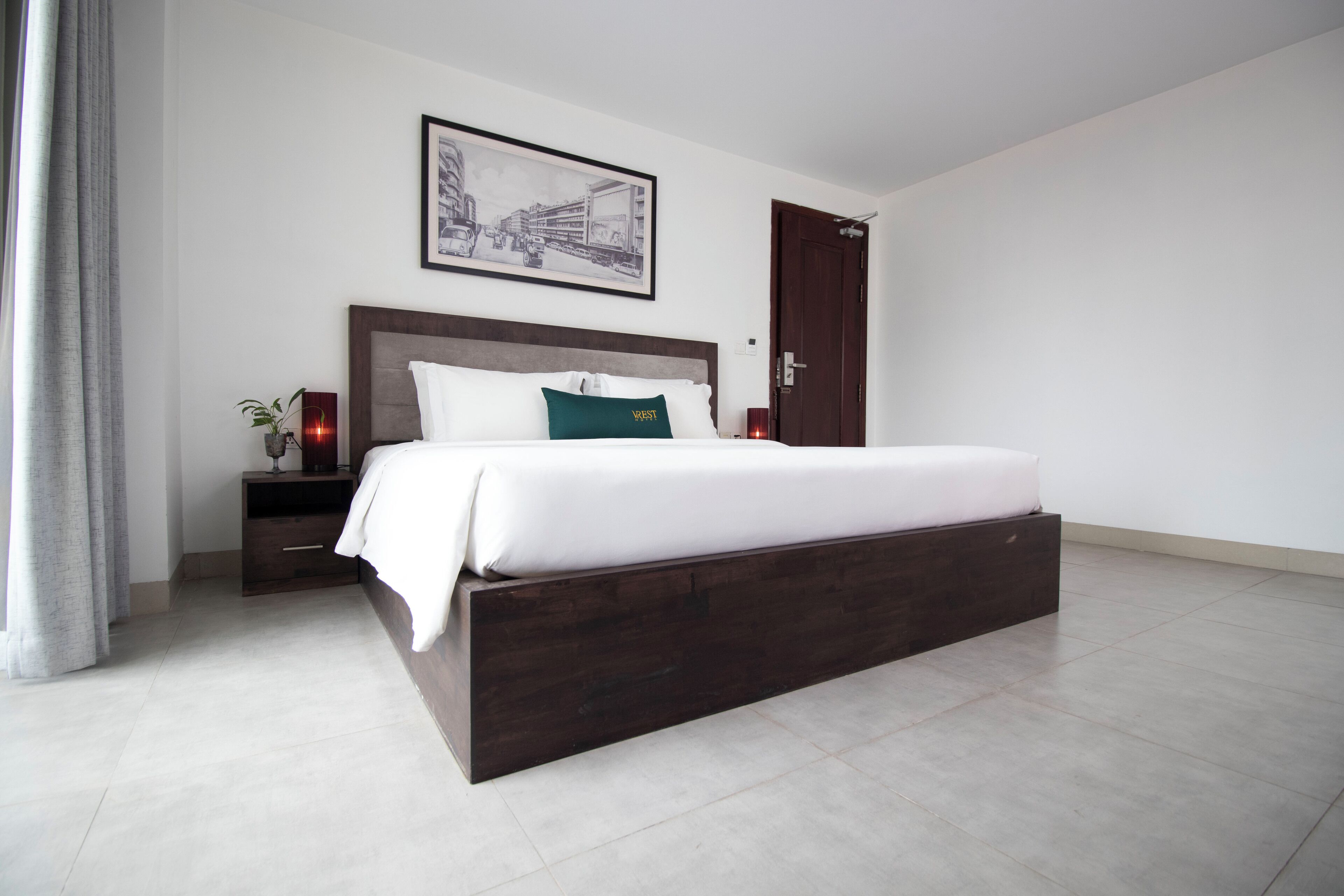 A modern bedroom with a large bed, a nightstand, a bedside table, and a framed picture on the wall.