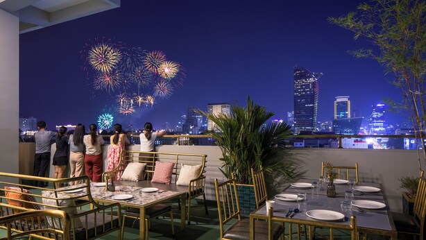 A rooftop dining area with tables and chairs, a city skyline in the background, and fireworks display. - Vrest Hotel  (Phnom Penh)