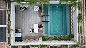An aerial view of a rooftop pool area with seating arrangements, a pool, and surrounding greenery. - Vrest Hotel  (Phnom Penh)