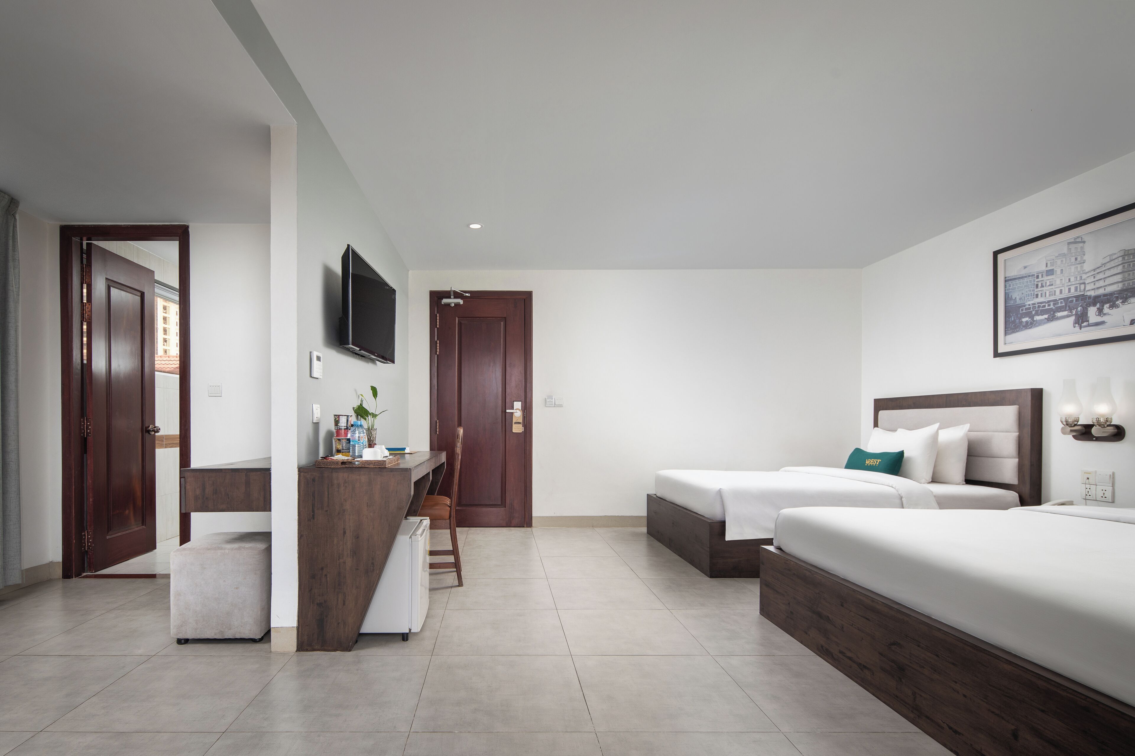 A modern hotel room with two beds, a desk, a chair, and a TV.