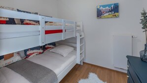 Une chambre avec des lits superposés, un radiateur, un tableau et une plante.