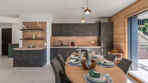 Une cuisine moderne avec des meubles de couleur sombre, un îlot central en bois et des luminaires suspendus.
