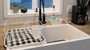 A kitchen with a white sink, a window with a view of houses, and a coffee maker. - Country Escape on 32 Acres/Trough Pool, Hot Tub & Stunning Views (Dayton)