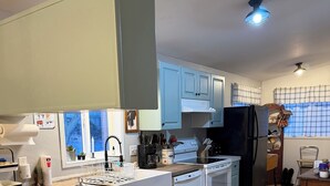 A kitchen with white cabinets, a wooden island, a black refrigerator, and a dining area with a chair. - Country Escape on 32 Acres/Trough Pool, Hot Tub & Stunning Views (Dayton)