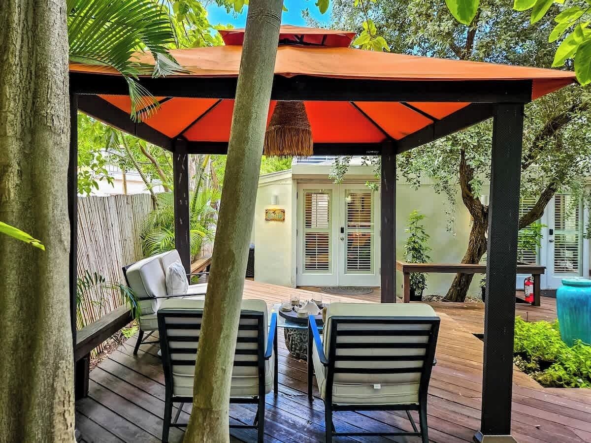 A wooden deck with a covered seating area, a small table, and chairs.