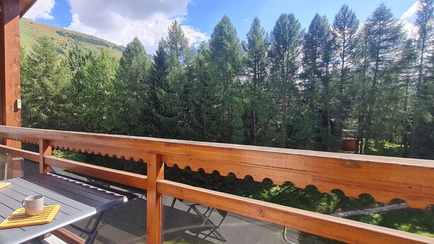 Eine Holzterrasse mit Tisch und Stühlen mit Blick auf einen bewaldeten Hang.