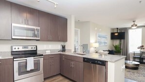 A modern kitchen with stainless steel appliances, wooden cabinets, and a granite countertop. - The Trinidad at 514 Jackson (Oxford)
