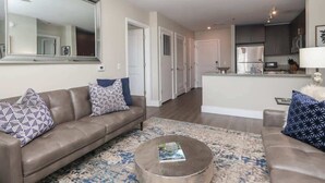 A modern living room with a sofa, coffee table, and a large mirror. - The Trinidad at 514 Jackson (Oxford)