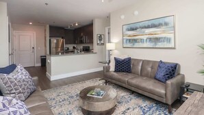 A modern living room with a sofa, coffee table, and a painting on the wall. - The Trinidad at 514 Jackson (Oxford)