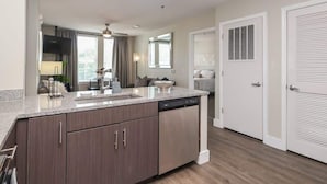 A modern kitchen with granite countertops, dark wood cabinets, and a dishwasher. - The Trinidad at 514 Jackson (Oxford)