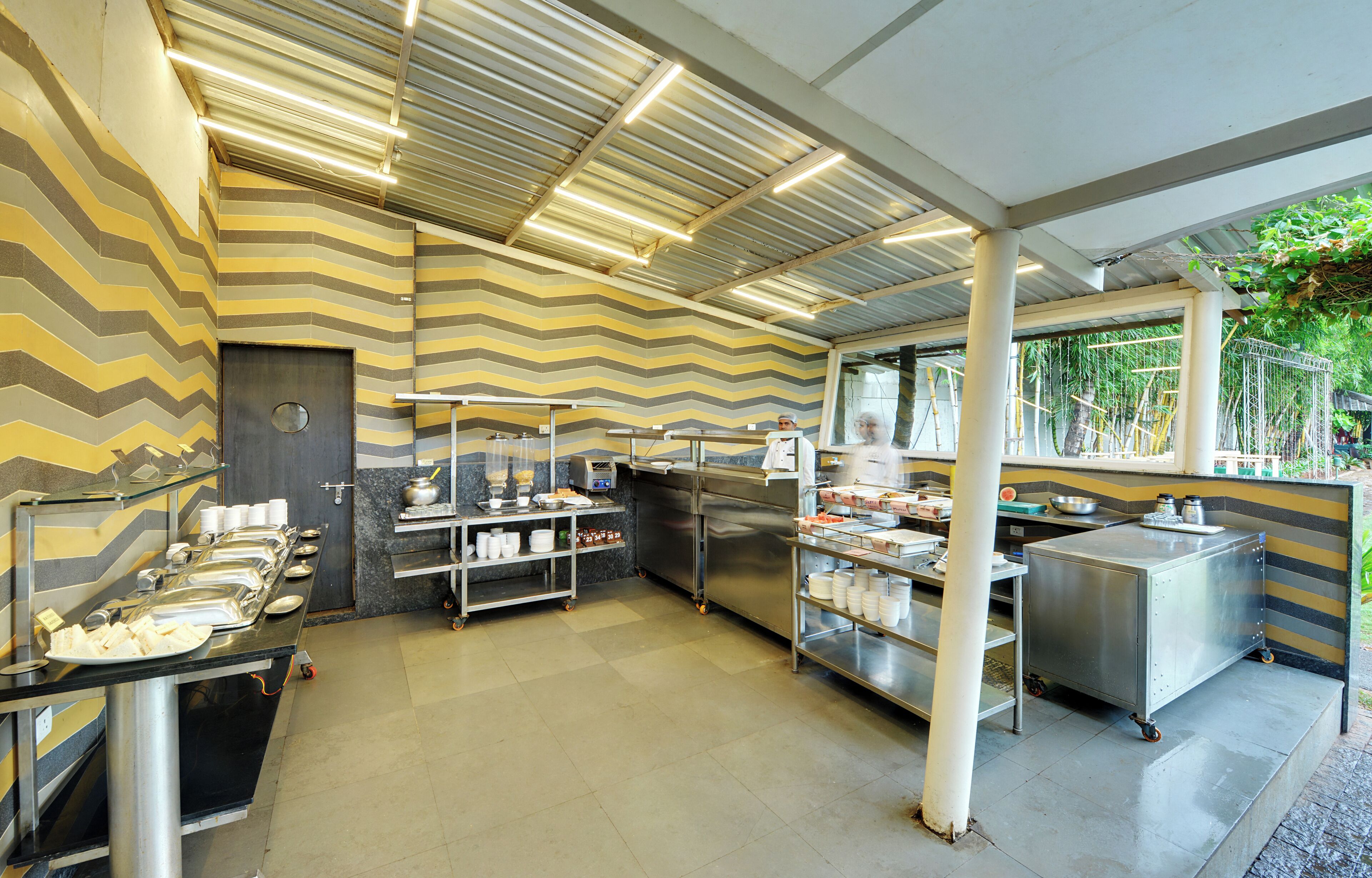 A modern kitchen with stainless steel appliances, a buffet setup, and a chevron-patterned wall.