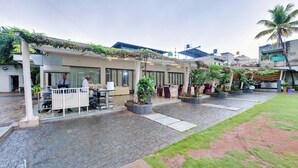 A hotel courtyard with outdoor seating, potted plants, and a covered area with tables and chairs. - Hotel Sankam Residency (Belagavi)