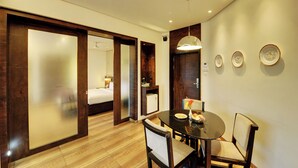 A hotel room with a bed, a dining area with a table and chairs, and a small kitchen area. - Hotel Sankam Residency (Belagavi)