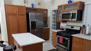 Una cocina moderna con electrodomésticos de acero inoxidable, armarios de madera y encimera blanca.