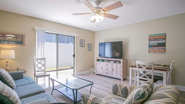 Un salon avec un canapé, une table basse, un téléviseur et un ventilateur de plafond.