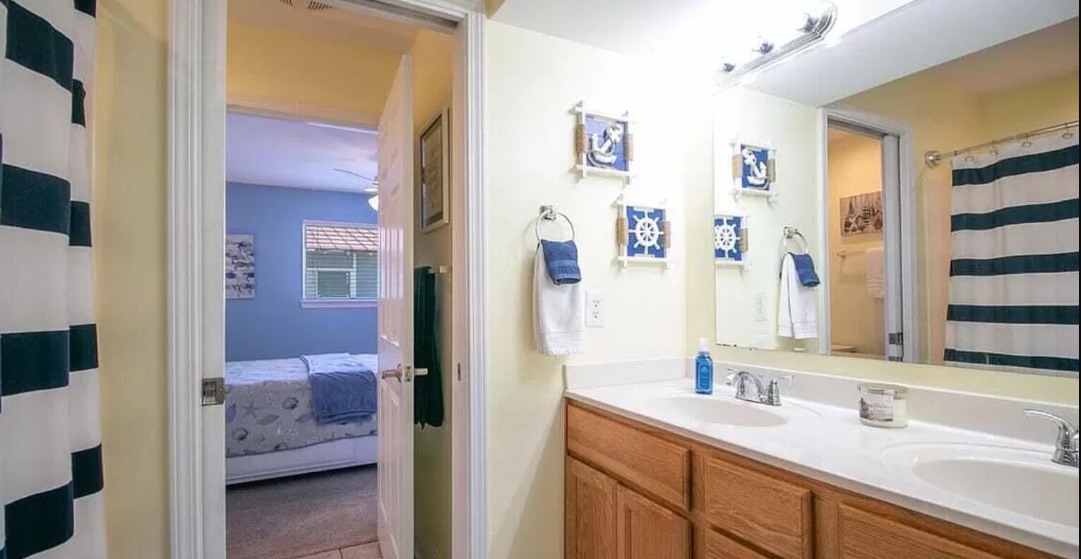 A bathroom with a large mirror, two sinks, and nautical-themed decorations.