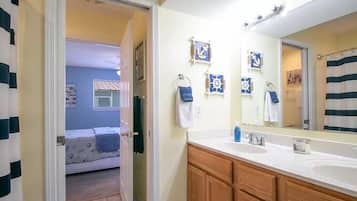 A bathroom with a large mirror, two sinks, and nautical-themed decorations.