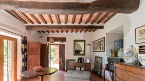 A rustic room with a wooden ceiling, a round table, a sofa, and a dresser with decorative items.