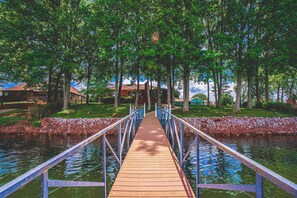 A wooden bridge over a body of water with metal railings, surrounded by trees and a grassy area. - Waterfront Access | Lake Views | Dock | Pool Table (Estill Springs)