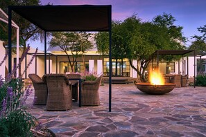 An outdoor patio with wicker furniture, a fire pit, and a covered seating area.