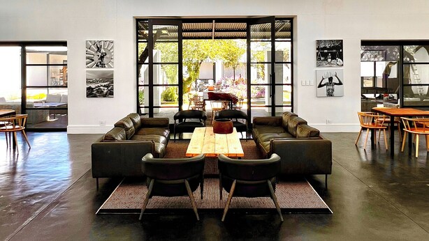 Ruime lounge met een hoge plafond, grote ramen en een centrale zithoek.