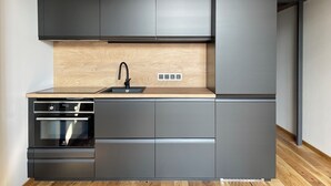 A modern kitchen with grey cabinets, a wooden countertop, a black faucet, and an oven.