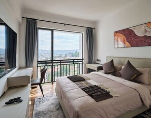 Contemporary hotel room with a large bed, desk, and city view.