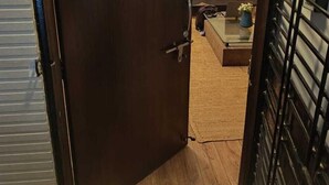 A door with a circular sign reading "Daisy Duplex" and a view into a room with a sofa and a coffee table. - Daisy Duplex (Nagpur)