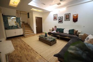 A living room with a sofa, a coffee table, a staircase, and a door. - Daisy Duplex (Nagpur)